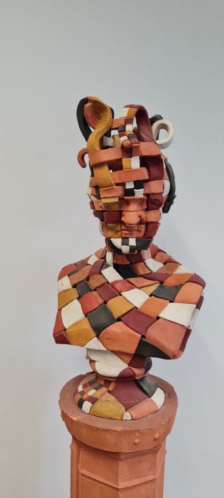 Photo of a colourful terracotta bust on a pedestal in front of a wall