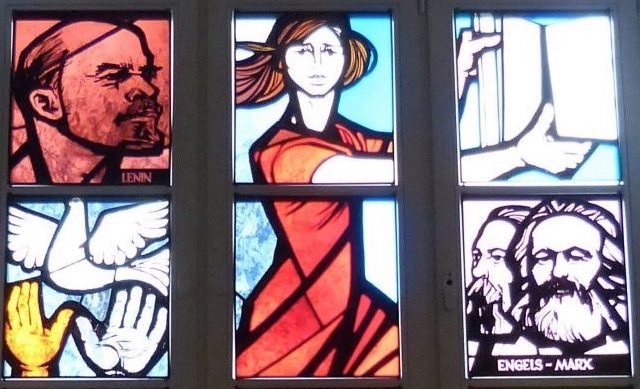 Ausschnitt Foto eines hohen Glasfensters, unterteilt in mehrere Scheiben mit verschiedenen Motiven des sozialistischen Menschen und der von ihm beherrschten Technik und Kunst