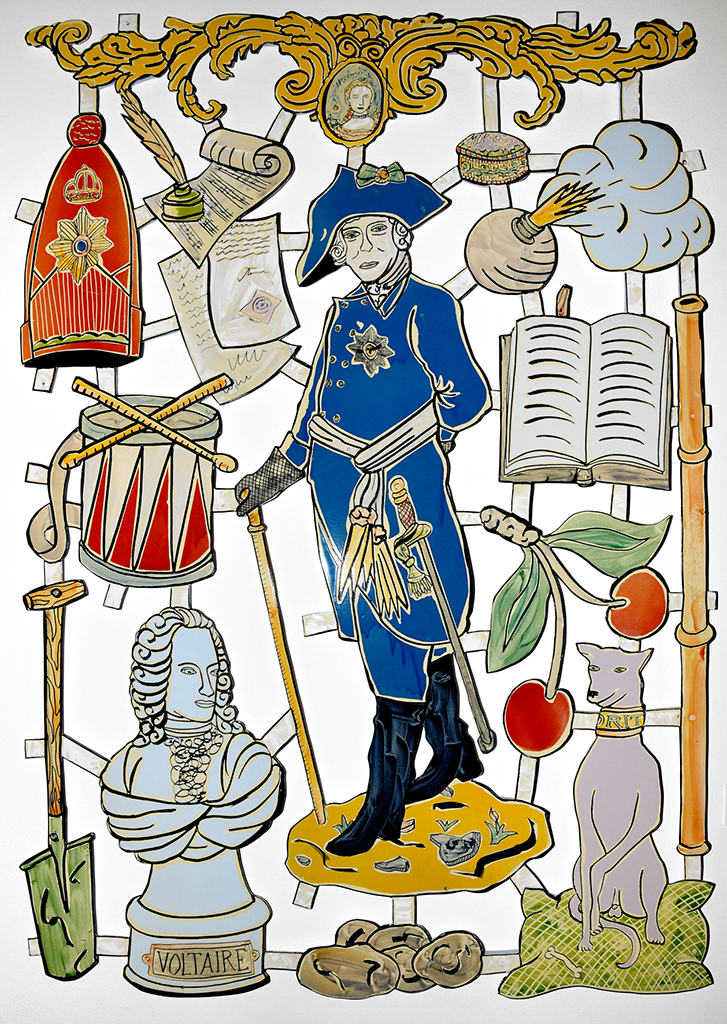 Foto einer an der Wand montierten Collage, die Friedrich II. und ihm zugeordnete Attribute zeigt.